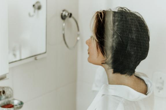 Woman looking into the bathroom mirror.