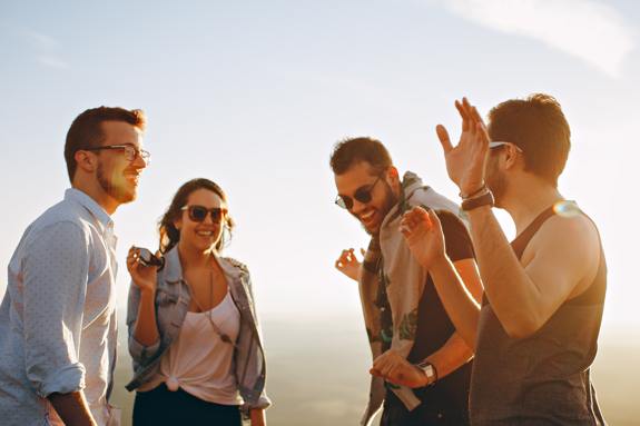 Friend group of four laughing at sunset.